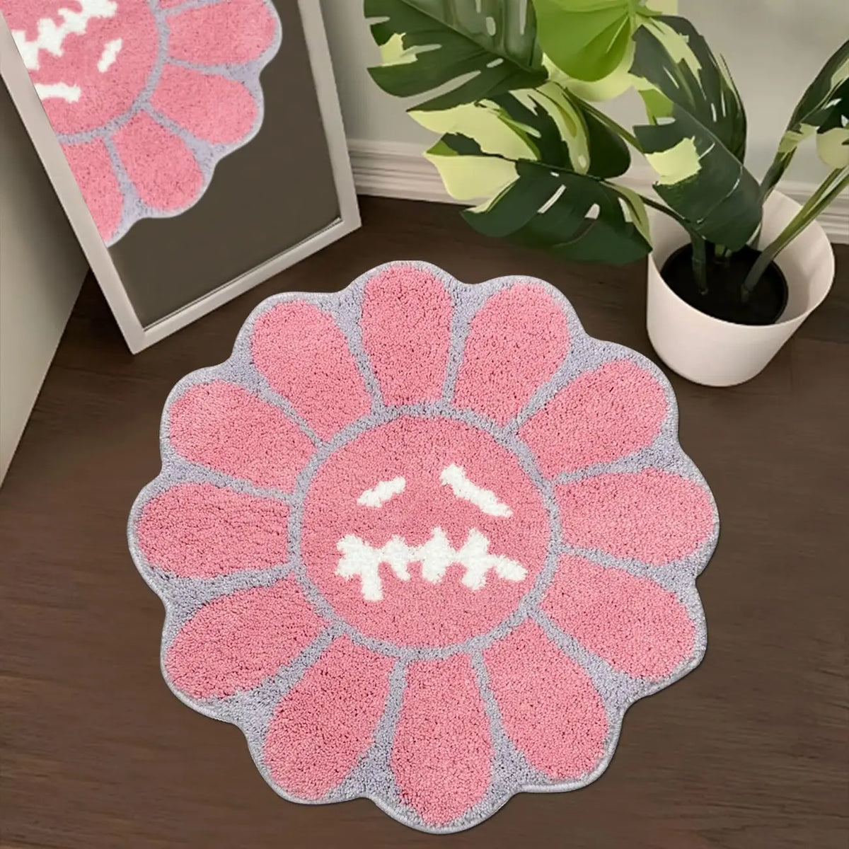 A pink and gray sunflower patterned absorbent non-slip bathroom mat on a wooden floor.