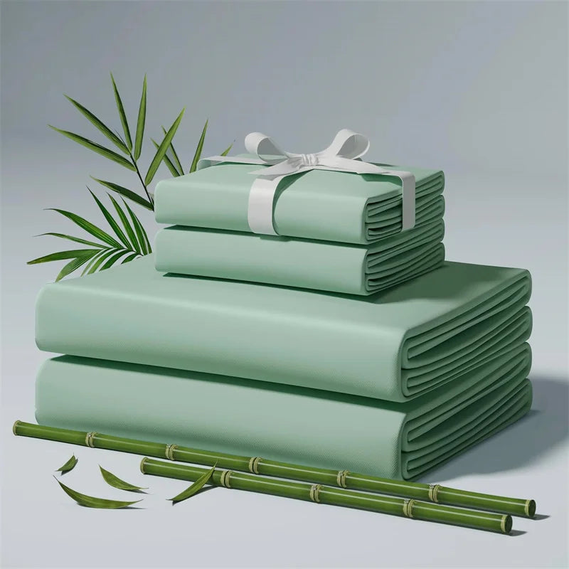 A stack of light green bamboo bed sheets rolled and tied with a white ribbon, resting on a surface with green leaves.