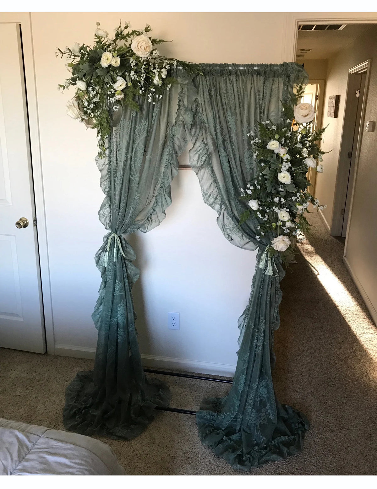 A sheer floral lace curtain panel in sage green hangs as a decorative backdrop.