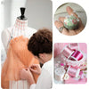 A person is using transparent diamond pins for crafting on a dress form, with rolls of pink and white craft material nearby.