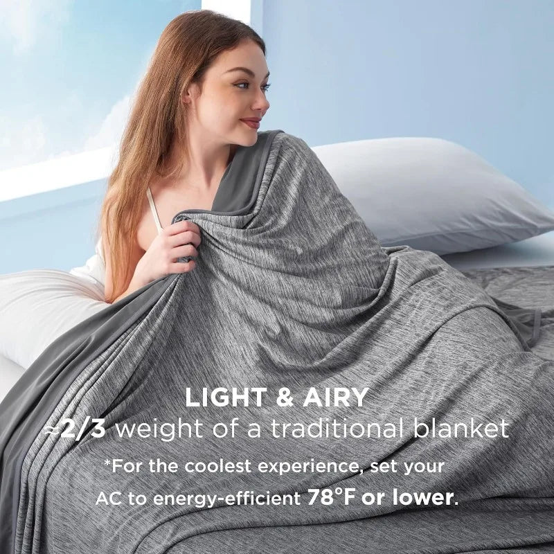 A woman is draping a gray lightweight blanket over a pillow in a bright room.