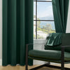 A dark green blackout window curtain framing a view of mountains and water from a window seat.