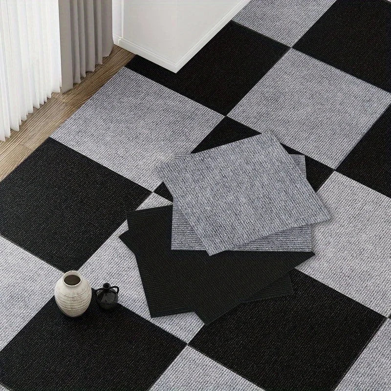 Stack of gray square carpet tiles on a black and gray checkered floor.