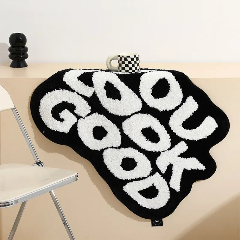 A black foot mat with white text spelling GOODUK is displayed on a light-colored surface.