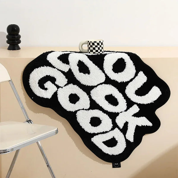 A black foot mat with white text spelling GOODUK is displayed on a light-colored surface.