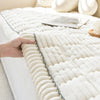 A hand touches a white, textured corduroy sofa armrest cover with vertical pleats.