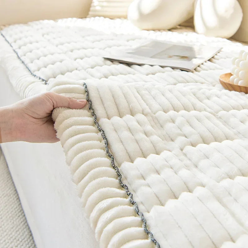 A hand touches a white, textured corduroy sofa armrest cover with vertical pleats.
