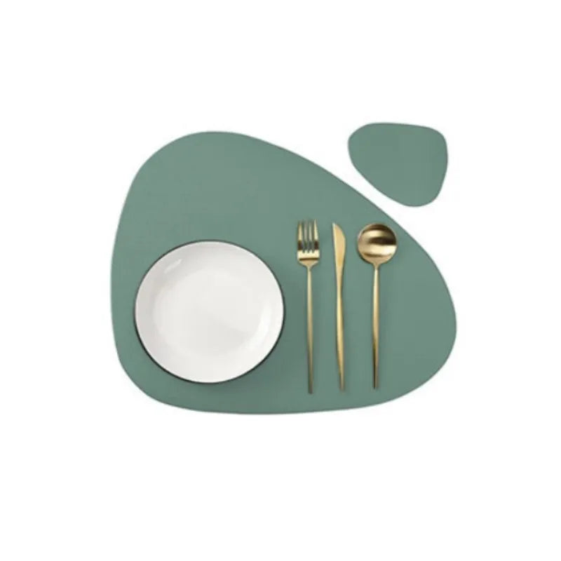 A set of gold-toned cutlery resting on a light green, organic-shaped placemat.