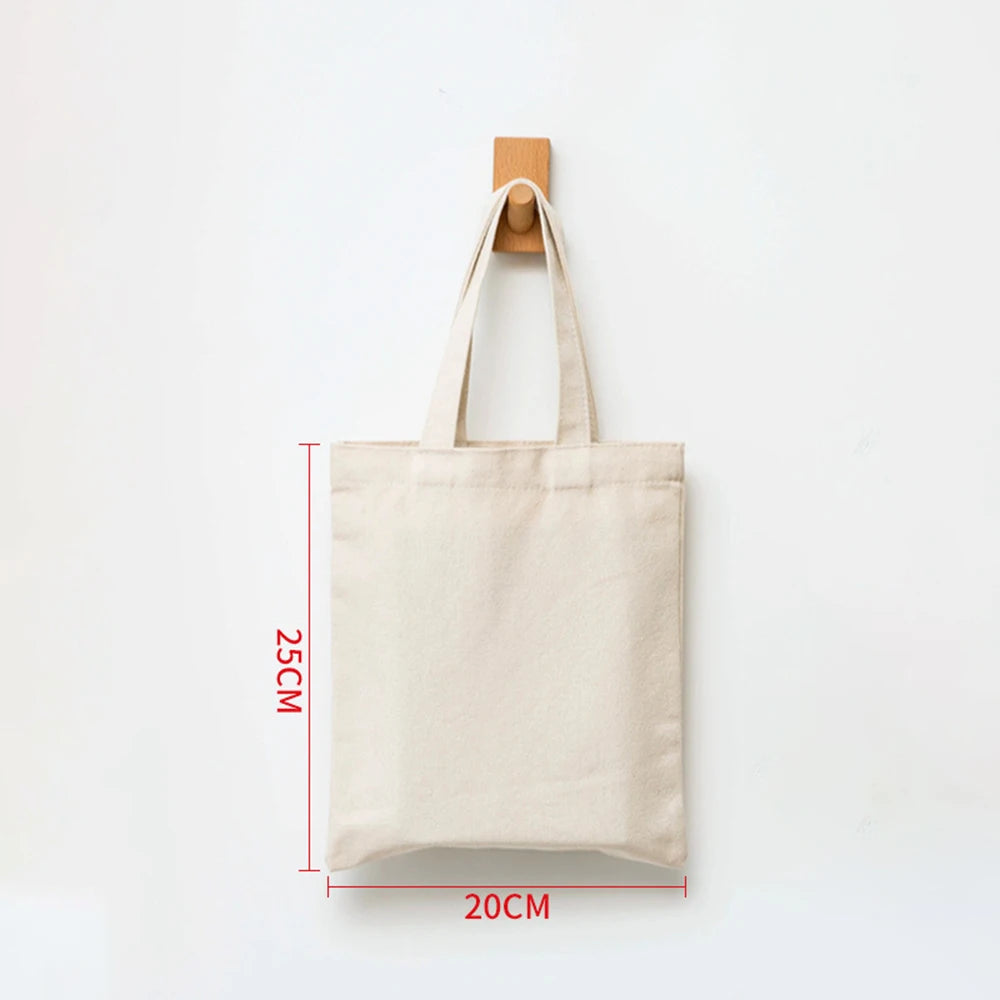 A beige canvas tote bag hanging against a white background with dimension markings.