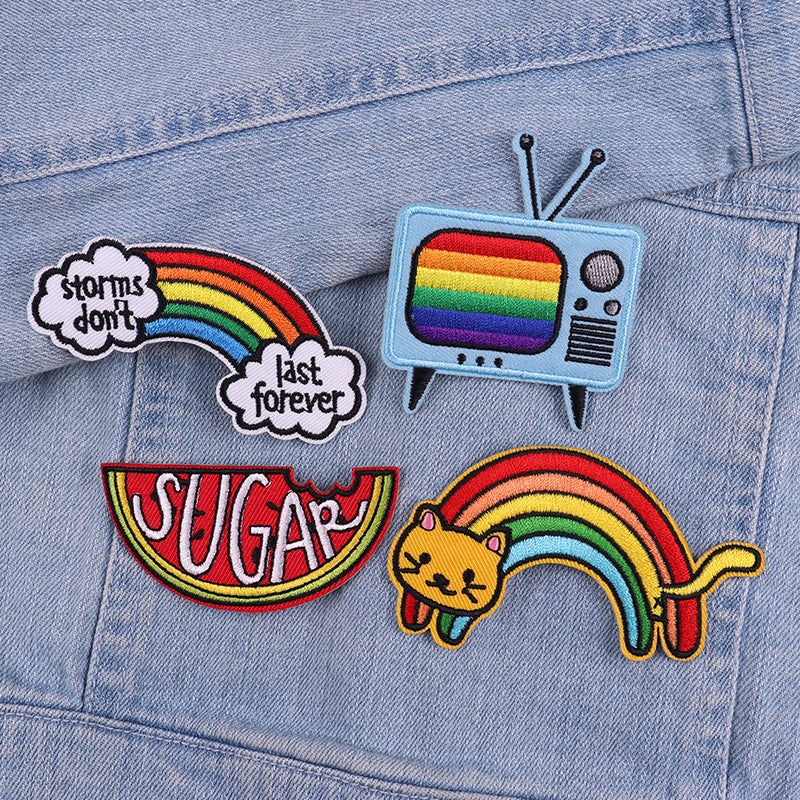 Embroidered letter patches featuring a rainbow, television, and cat design on a denim jacket.