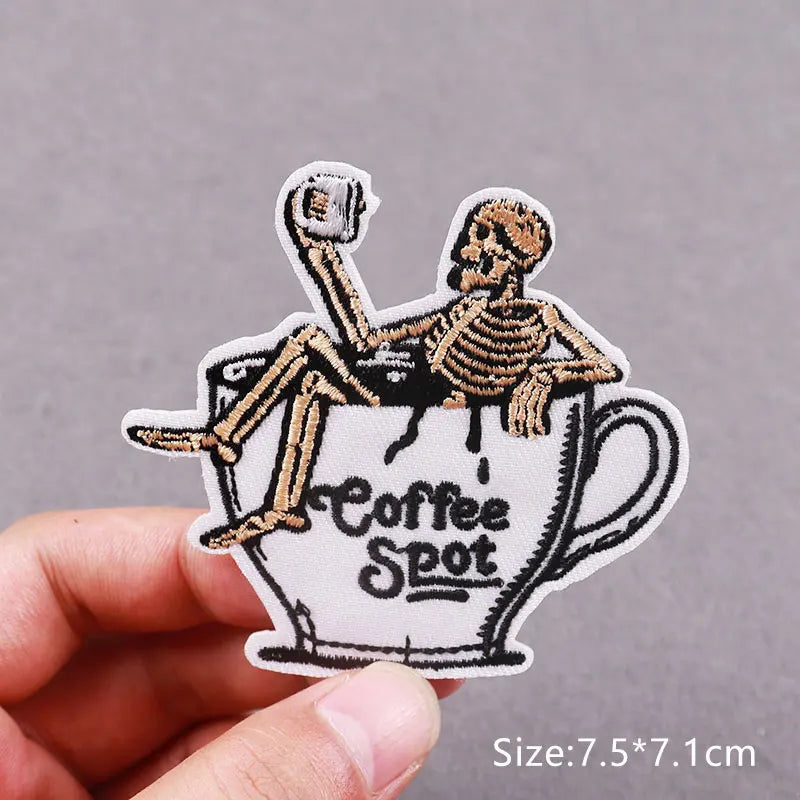An embroidered patch depicting a skeletal figure sitting in a coffee cup, labeled Coffee Spot.
