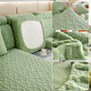 A textured moss green plush velvet sofa cover with a quilted pattern and a smooth white backing.
