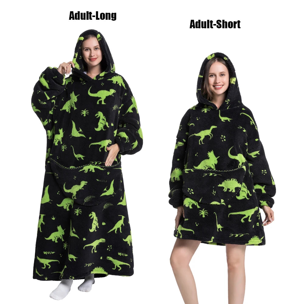 A woman models an adult-long and adult-short plush fleece blanket hoodie featuring a green dinosaur pattern on a black backgr