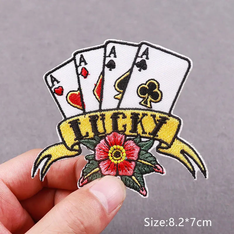 An embroidered patch featuring a hand of playing cards with a banner that reads LUCKY