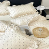 A set of white Korean lace duvet covers and pillows with subtle polka dots on a bed.