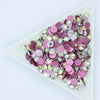 A rectangular tray filled with pink and purple crystal flatback rhinestones for crafts and decor