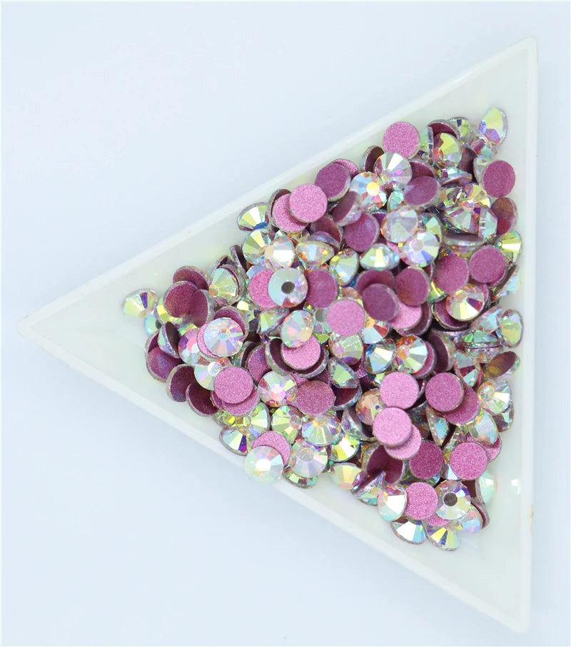 A rectangular tray filled with pink and purple crystal flatback rhinestones for crafts and decor