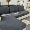 A gray jacquard knit sofa cushion cover is shown on a light-colored sofa, with a decorative plant in the background.