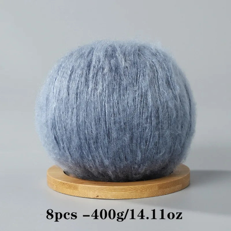 A ball of gray mohair yarn resting on a wooden base.