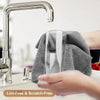 A hand is wiping a stainless steel kitchen faucet with a gray microfiber cleaning wipe.