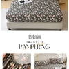 A floral printed cotton fitted sheet in shades of green and pink is displayed on a bed with a white headboard.