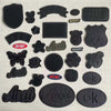 A set of black embroidered leather patches featuring various designs like a shield, a bear, and text such as AMAZING and ROUT