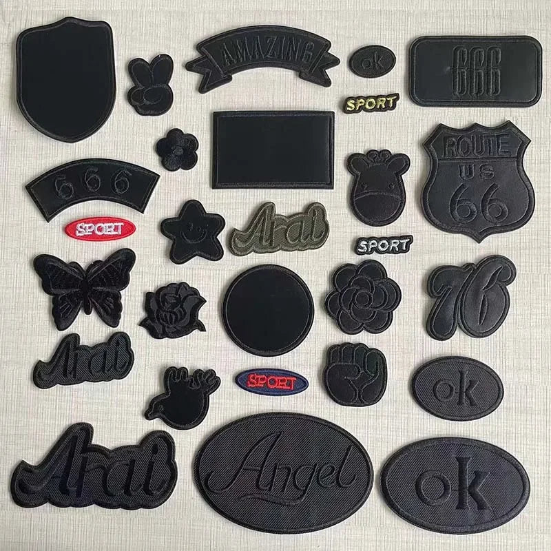 A set of black embroidered leather patches featuring various designs like a shield, a bear, and text such as AMAZING and ROUT