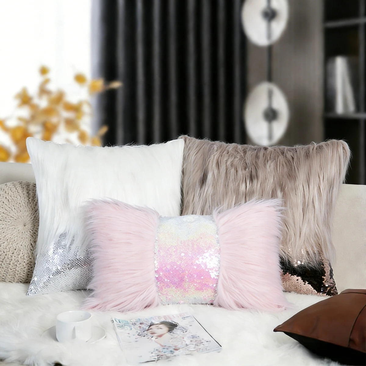 A pink sequin fur cushion cover resting on a white fluffy surface with other light-colored pillows.