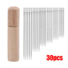 A set of 30 metal hand sewing needles stored in a wooden cylinder.
