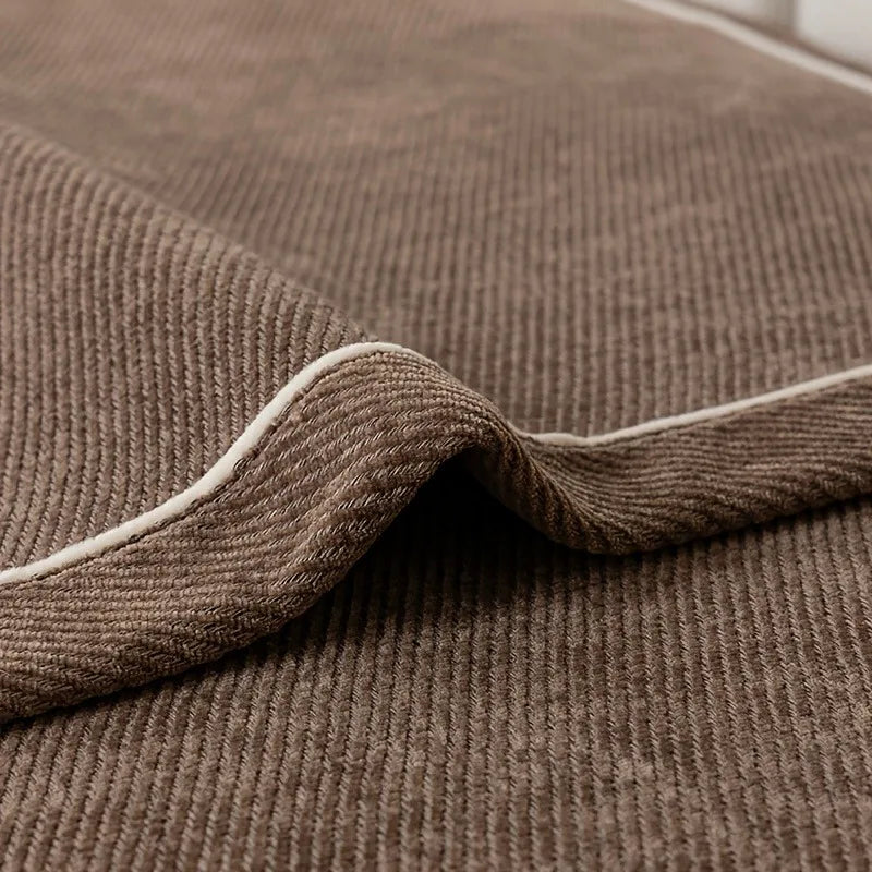 Close-up of a brown chenille sofa protector cover showing the textured fabric and rolled edge.