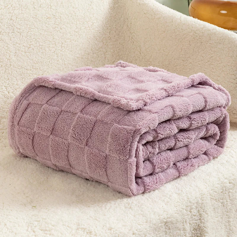 A folded lavender checkered fleece throw blanket resting on a light-colored, textured surface.