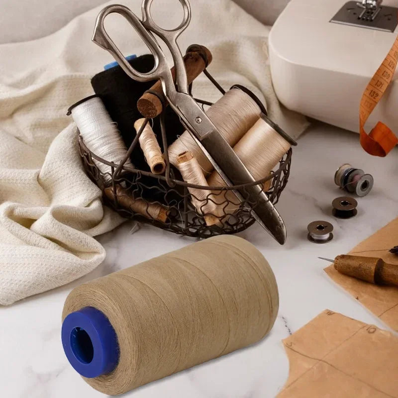 A collection of sewing thread spools and scissors on a white marble surface with a beige cloth.