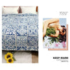 A blue and white embroidered cotton quilted bedspread with floral patterns displayed next to a yellow flower.