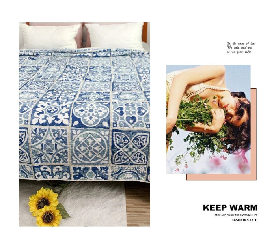 A blue and white embroidered cotton quilted bedspread with floral patterns displayed next to a yellow flower.