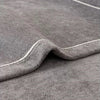 A close-up of a gray chenille sofa protector cover showing a folded edge and subtle texture.