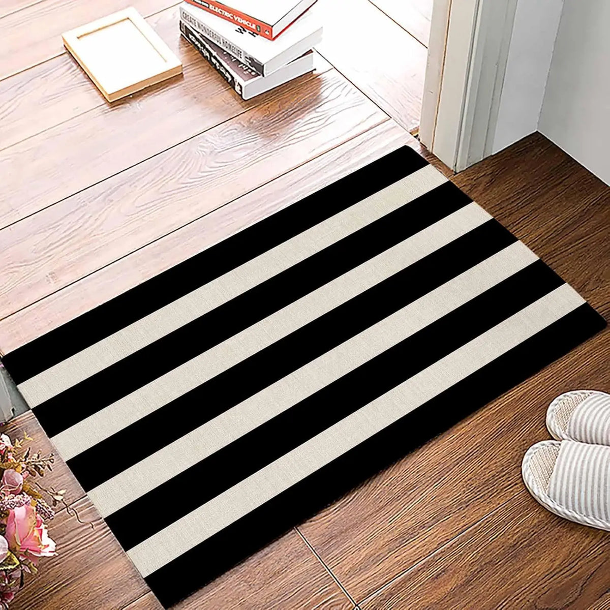 A black and white striped anti-slip door mat placed on a wooden floor.