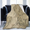 A beige blanket featuring a detailed map of Middle-earth, displayed on a dark sofa.
