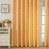Floor-length, sheer gold curtains with a feather jacquard texture hanging in a light-colored room.