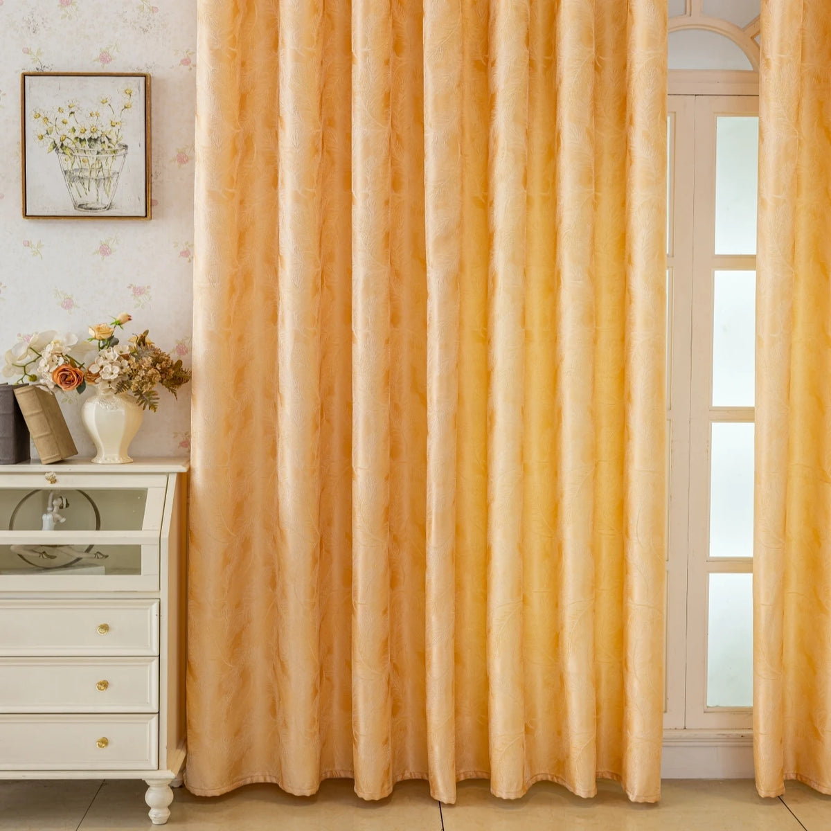 Floor-length, sheer gold curtains with a feather jacquard texture hanging in a light-colored room.