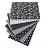 A stack of black and white patterned cotton fabric squares featuring floral, striped, and polka dot designs.
