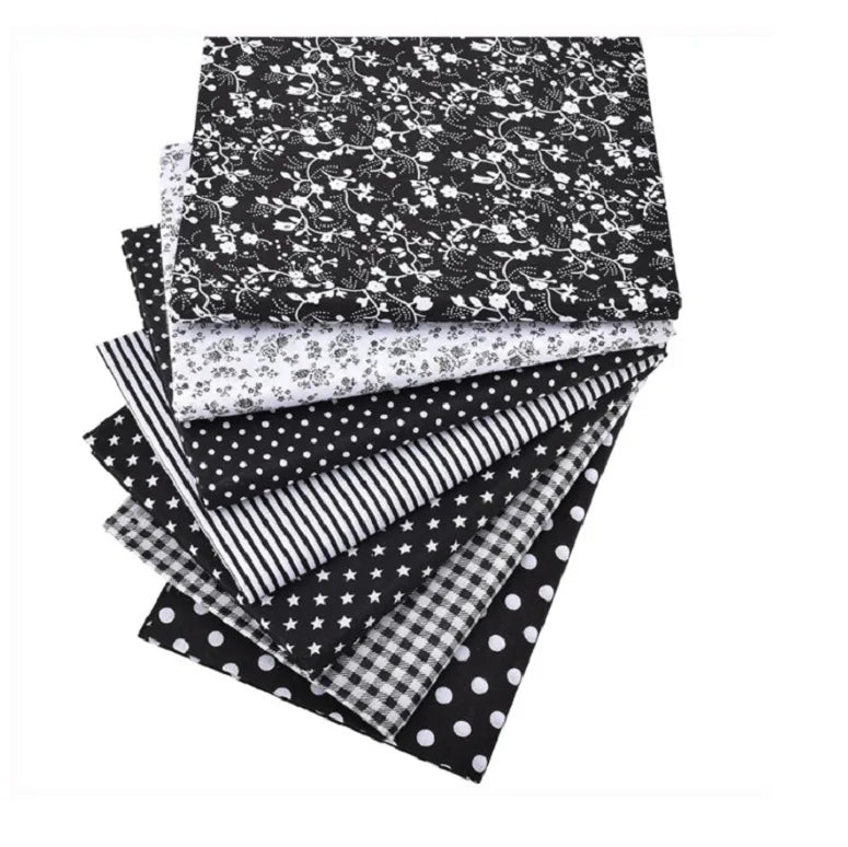 A stack of black and white patterned cotton fabric squares featuring floral, striped, and polka dot designs.