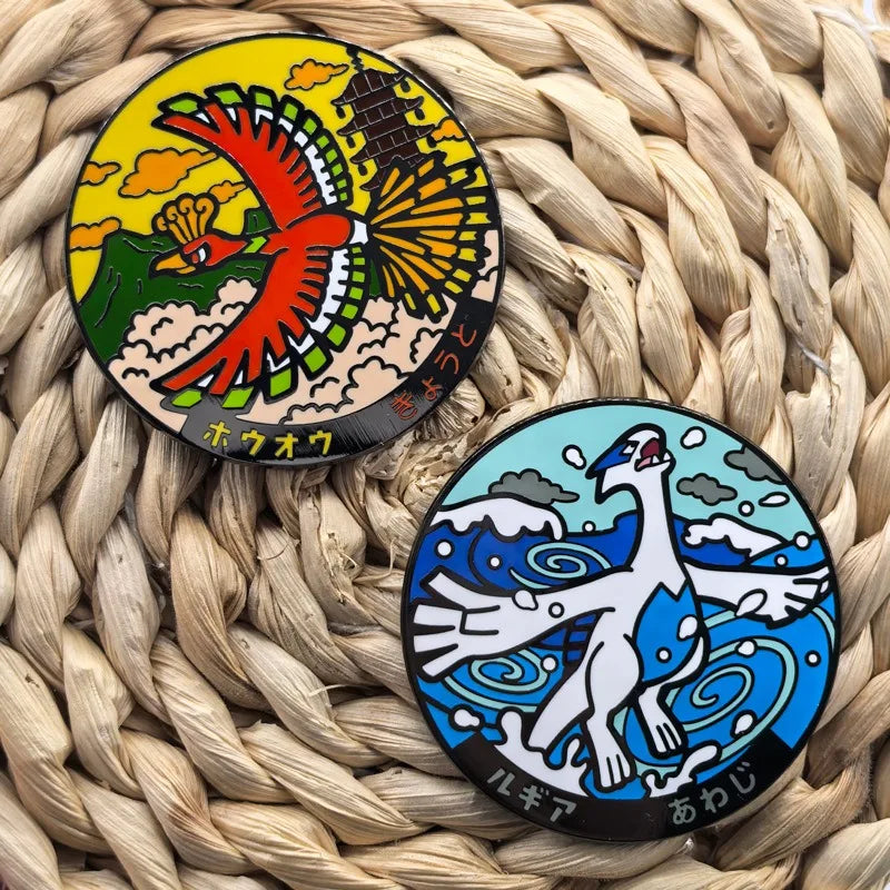 A pair of metal broach pins featuring the anime characters Ho-Oh and Lugia set against a woven straw background.