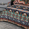 A close-up of a boho geometric duvet cover set featuring intricate patterns in teal, orange, brown, and navy on a bed.