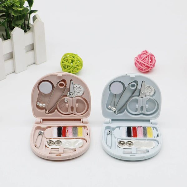 A portable DIY sewing box with pink and gray compartments and tools, next to a ball of green yarn.
