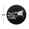 Black embroidery patch featuring a white bird with a yellow beak and orange feet, with the text Peace was never an option.