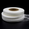 Roll of white double-sided fabric interlining tape on a black background