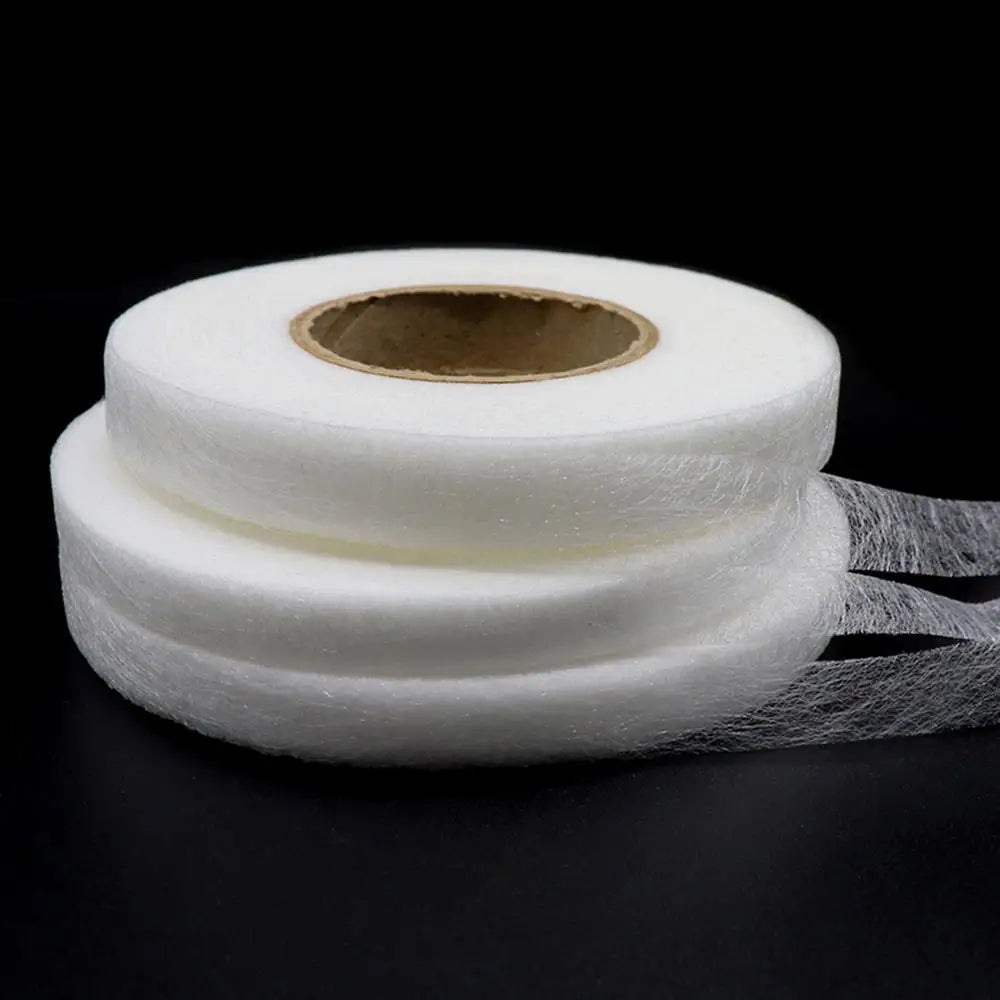 Roll of white double-sided fabric interlining tape on a black background