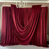 Deep red velvet draping fabric used as a backdrop for decor