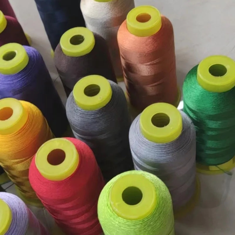 A collection of spools of high tenacity polyester sewing thread in various colors including purple, green, orange, and gray.
