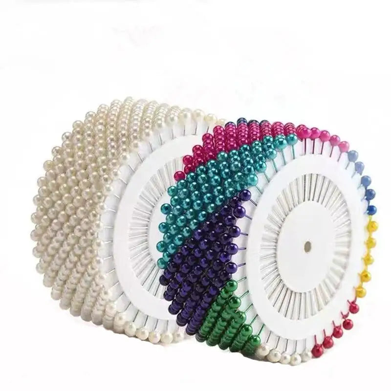 A collection of colorful pearl straight head pins arranged in a fan shape for crafting.